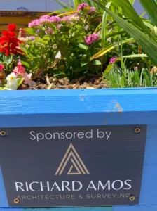 A blue painted planter with a sponsor plaque