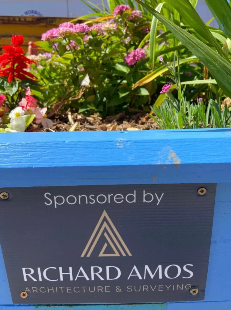 A blue painted planter with a sponsor plaque