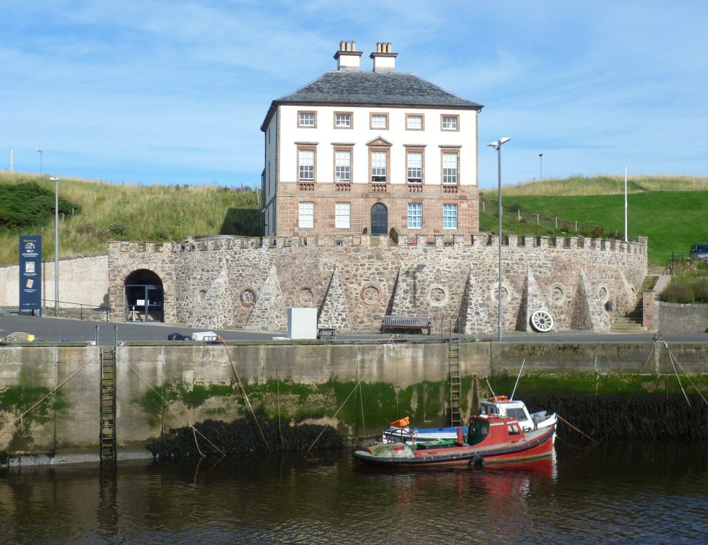 Gunsgreen House above the harbour wall, with a small red boat below