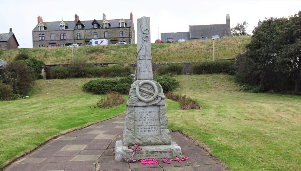 A stone memorial to the 1881 Eyemouth fishing disaster, with flowers at its base